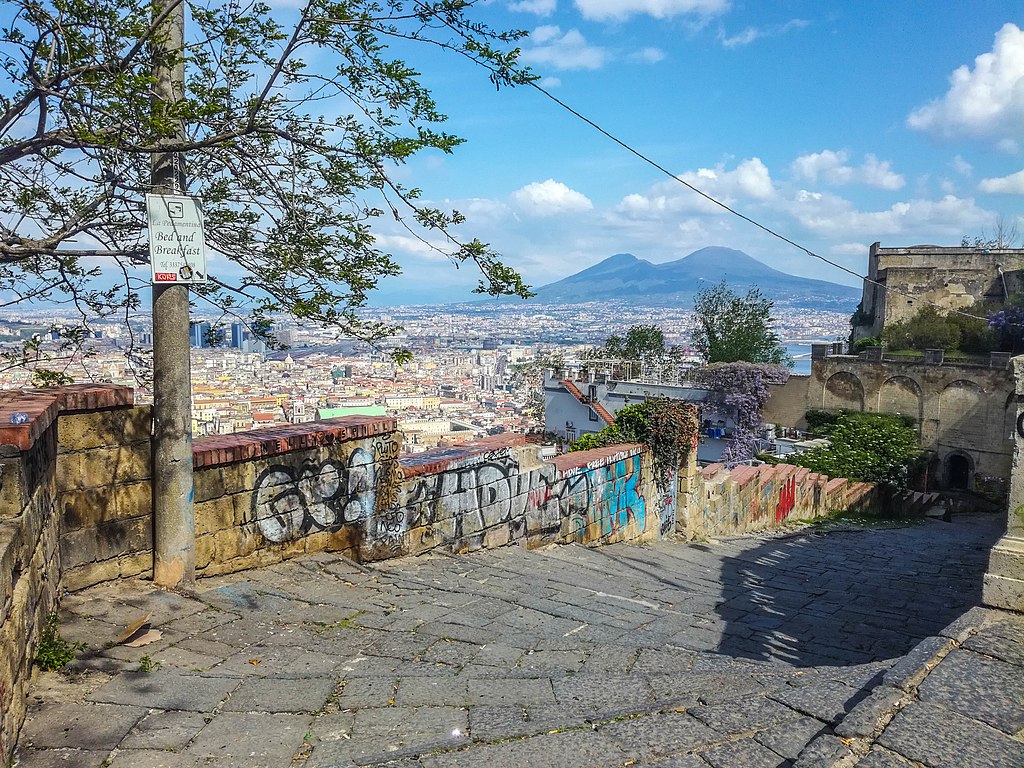 La Pedamentina, Naples. Stairs with views across city to Vesuvius. 
Attribution: Baku, CC BY-SA 4.0 <https://creativecommons.org/licenses/by-sa/4.0>, via Wikimedia Commons