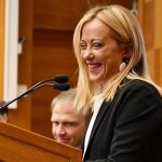 meloni smiling at lectern. Government talks still underway