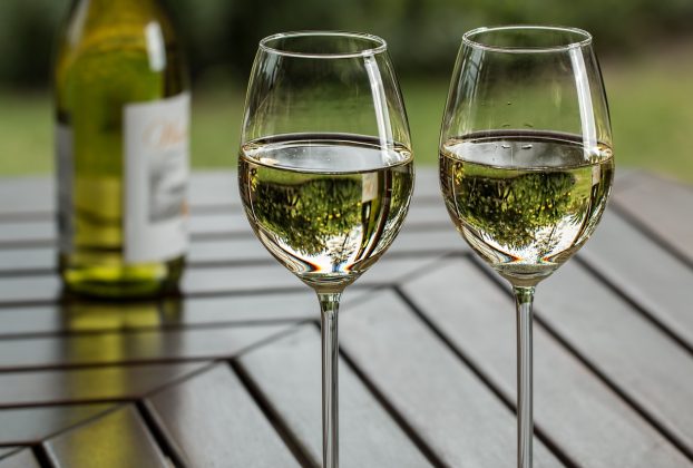 two wine glasses containing white wine and a bottle. Wine sector to receive support package