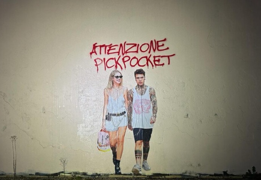 Mural of Chiara Ferragni shows her wealking with her husband, carrying a pandoro, under the title Beware Pickpocket.