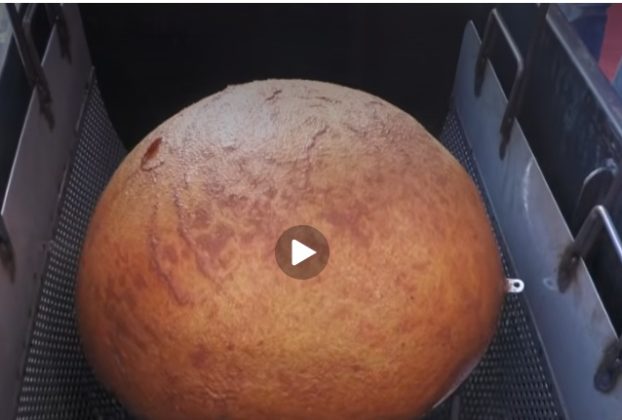 The biggest arancina in the world being lifted from the fryer. Still from video by Tele One