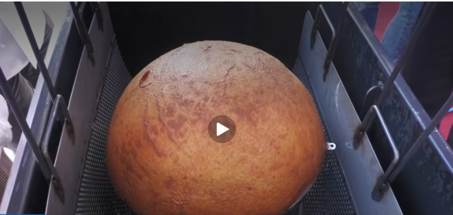The biggest arancina in the world being lifted from the fryer. Still from video by Tele One