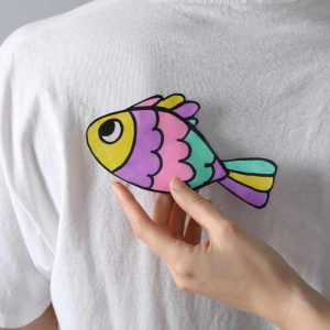 What's behind the tradition of the pesce d'aprile? Image shows someone sticking a colourful paper fish to the back of another.