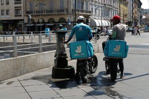Glovo and Deliveroo investigated by Antitrust Authority. Image shows two Deliveroo riders refilling water bottles in Italy.
