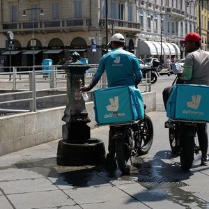 Glovo and Deliveroo investigated by Antitrust Authority. Image shows two Deliveroo riders refilling water bottles in Italy.