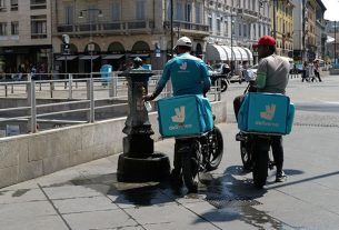 Glovo and Deliveroo investigated by Antitrust Authority. Image shows two Deliveroo riders refilling water bottles in Italy.