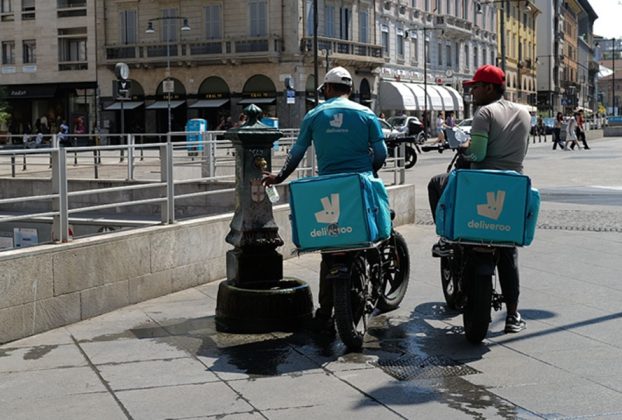 Glovo and Deliveroo investigated by Antitrust Authority. Image shows two Deliveroo riders refilling water bottles in Italy.
