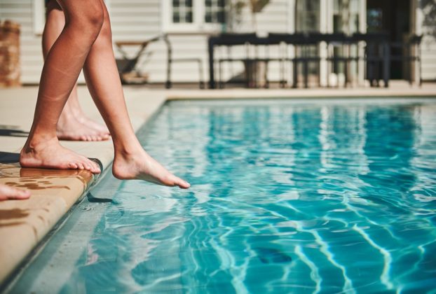 Image shows childrens feet and legs at edge of swimming pool. Pool safety in Italy is urgently being addressed