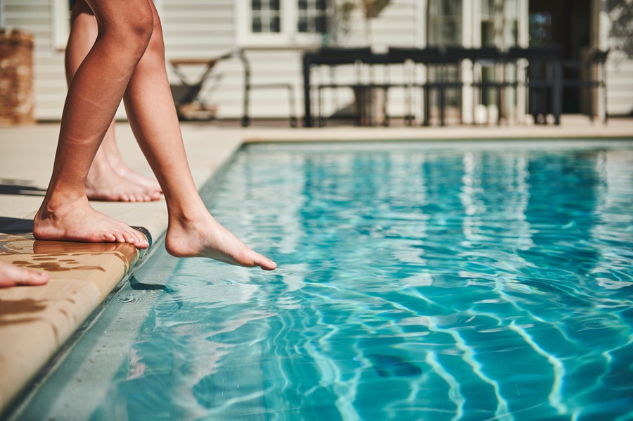 Image shows childrens feet and legs at edge of swimming pool. Pool safety in Italy is urgently being addressed
